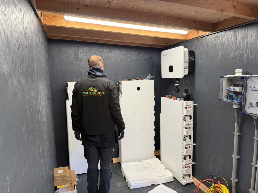 Monteur van Warmte Zon sluit een thuisaccu en omvormer aan in een technische ruimte